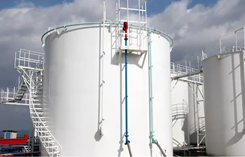 Industrial refinery tanks surrounded by a thick, chemical-resistant polyurea secondary containment lining.