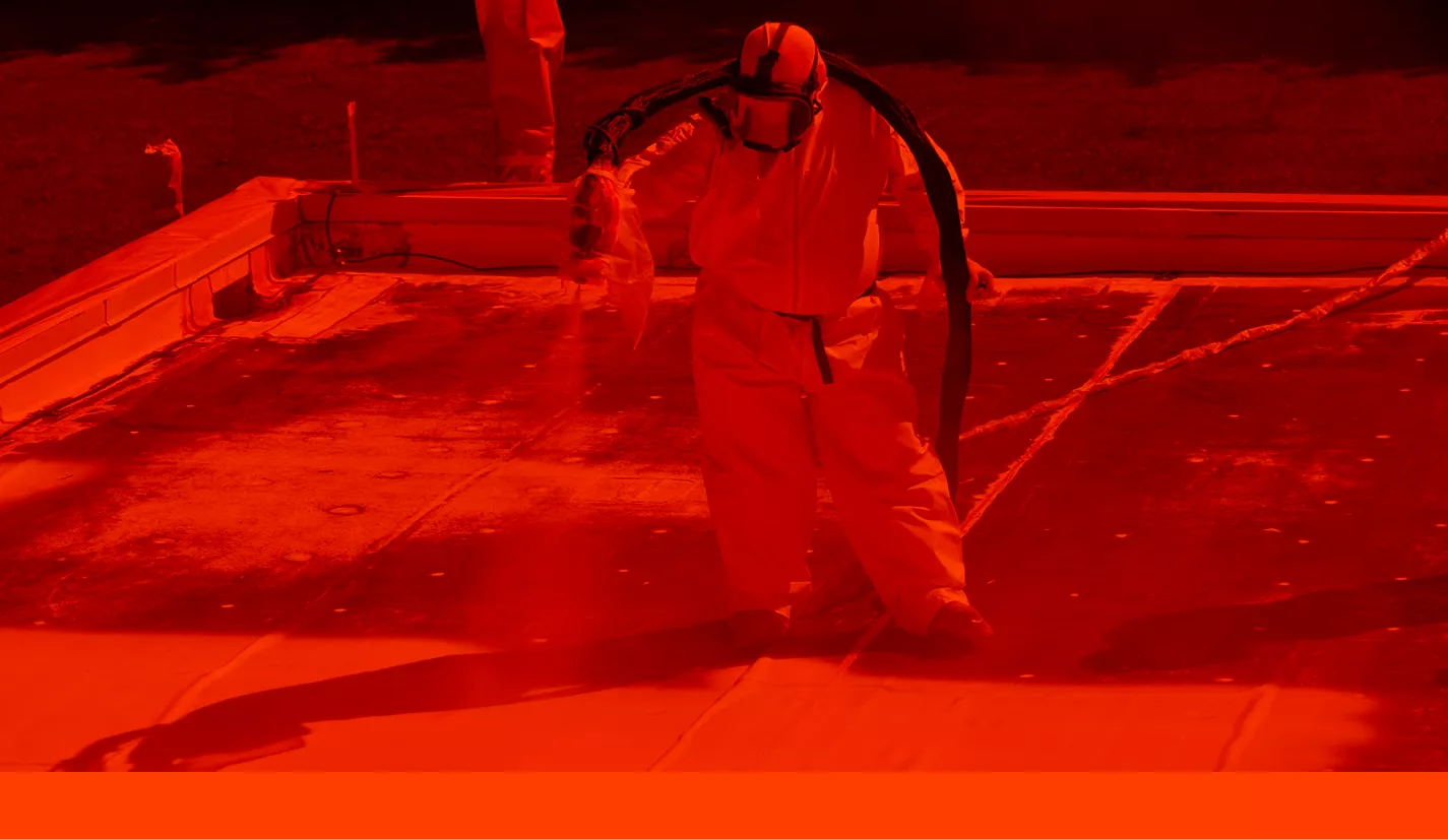 Professional insulation crew spraying rigid closed-cell polyurethane foam across a building wall assembly.